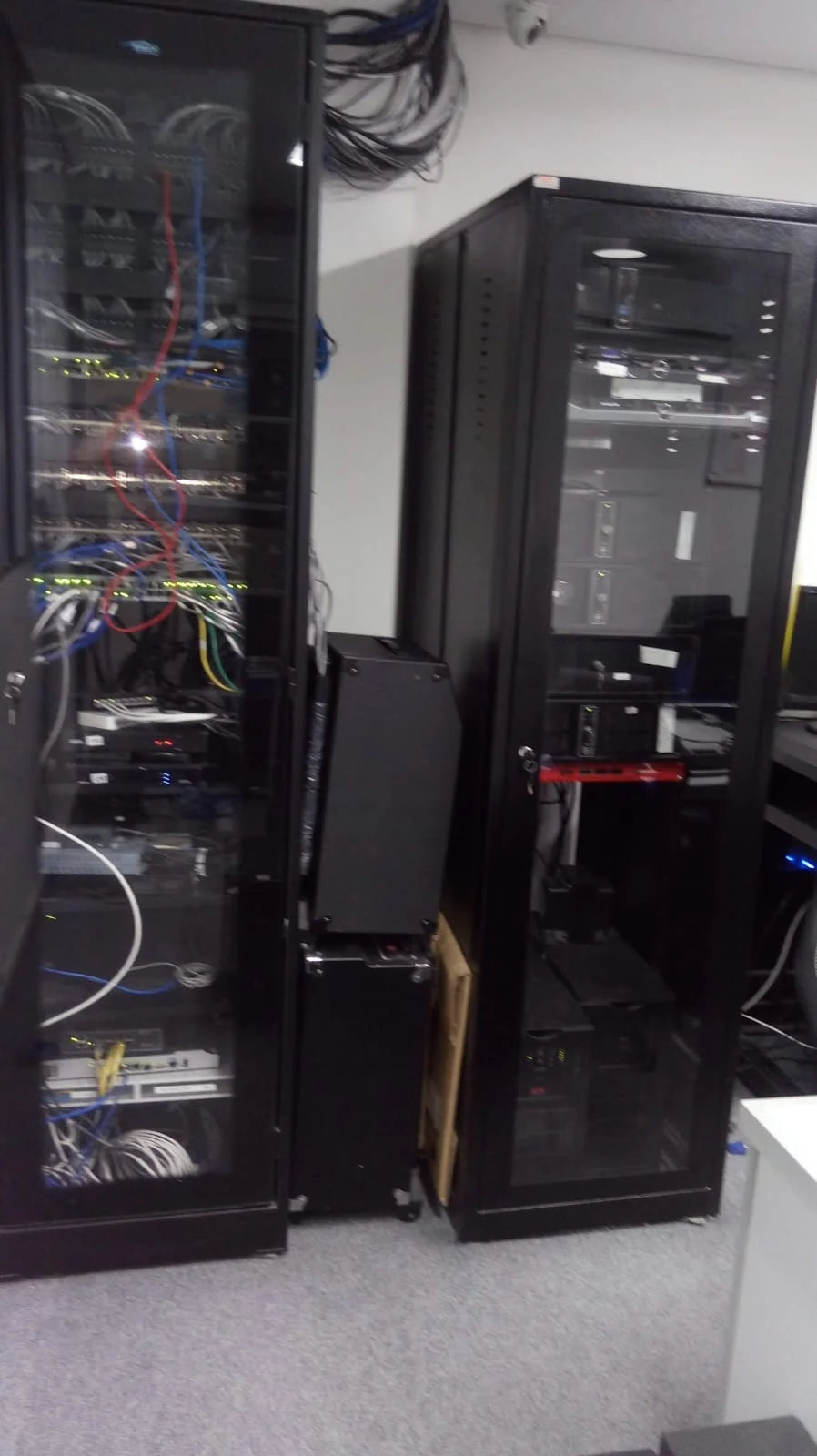 Ambiente corporativo com um rack dedicado a switches, roteadores e patch panels e outro aos servidores. O trabalho incluía a administração de todo o parque tecnológico da empresa.